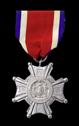 Silver cross with the seal of New York in the center hanging from a red, white, and blue ribbon. 