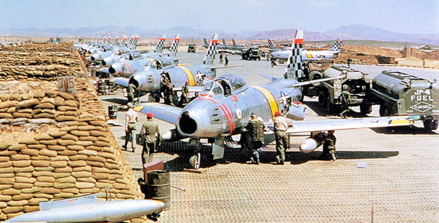 Multiple planes in a line at the airbase.