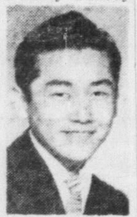 A picture of Kaneko, wearing a jacket and tie, smiling at the camera.