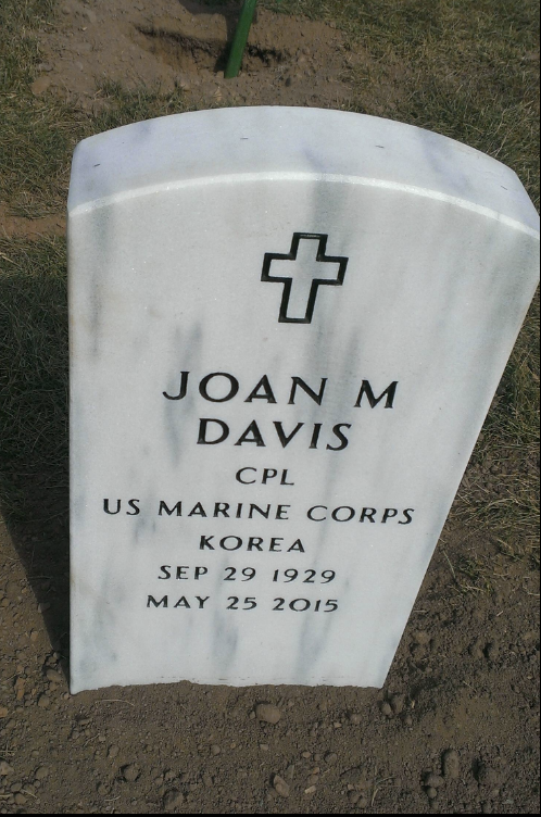 White grave stone with a with a cross outlined in black and black font that says Joan M. Davis.