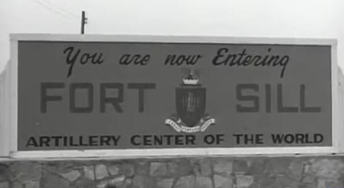 A large, rectangular sign sits atop a stone wall that reads “You are now entering Fort Sill Artillery Center of the World”