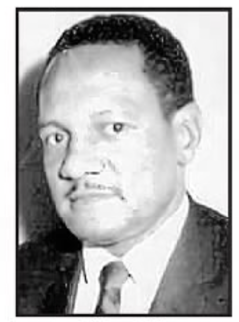 Leon Wesson looks directly into the camera. He is an African American male with short hair and a mustache. He is wearing a suit jacket and tie.
