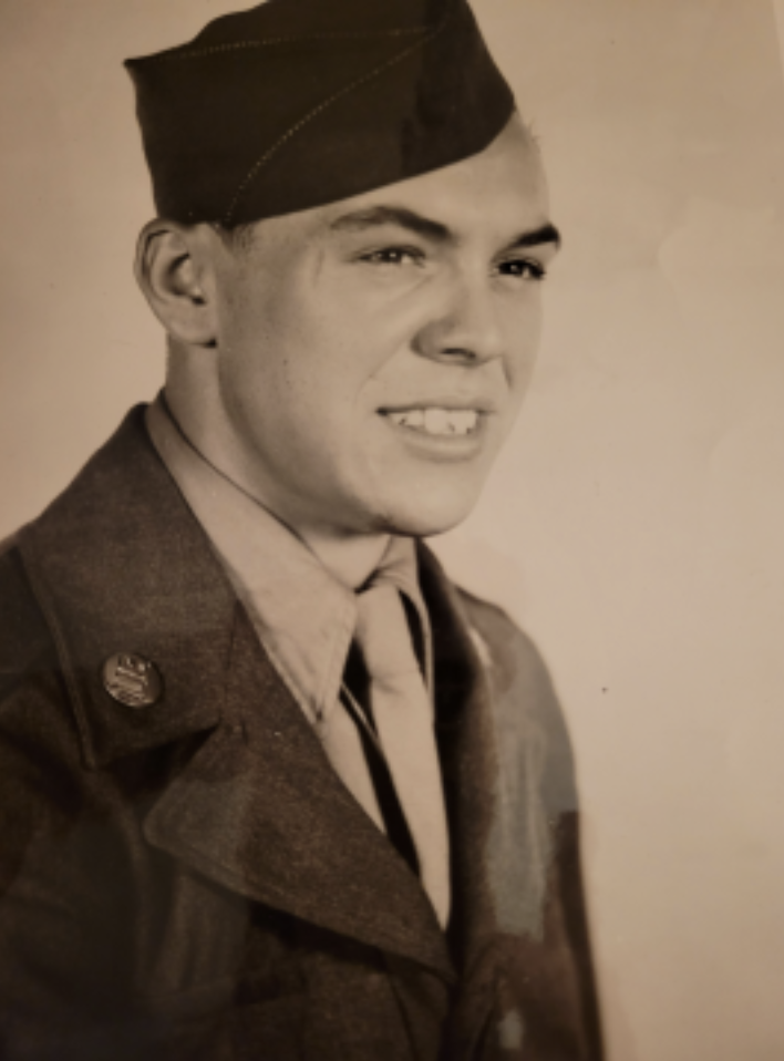 A young man wearing an Army dress uniform and cap.
