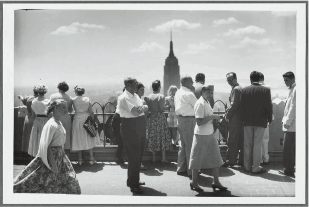 Black and White photo of many people standing atop the Empire State Building.