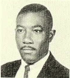 A clean-cut African-American man looks slightly off to the side. He is wearing a suit jacket and tie.