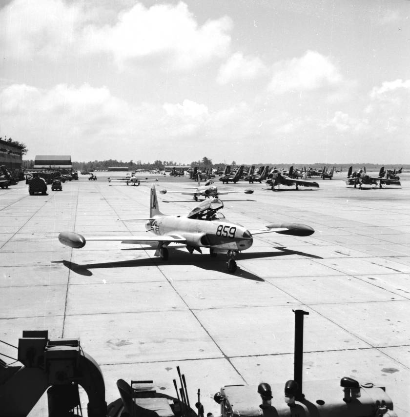A black and white image of several planes lined up at an airbase.