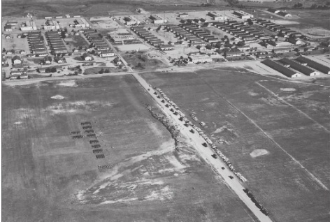 An aerial view of the base with a formation of troops in the foreground (front left) and the expansive quartermaster training facilities in the background.