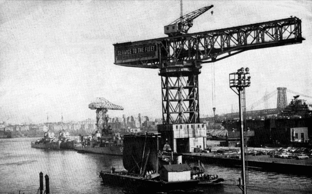 Photo of a naval shipyard with a crane in the center.