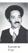 A black and white headshot of a young Black man with an afro. He is wearing a dark suit and tie.