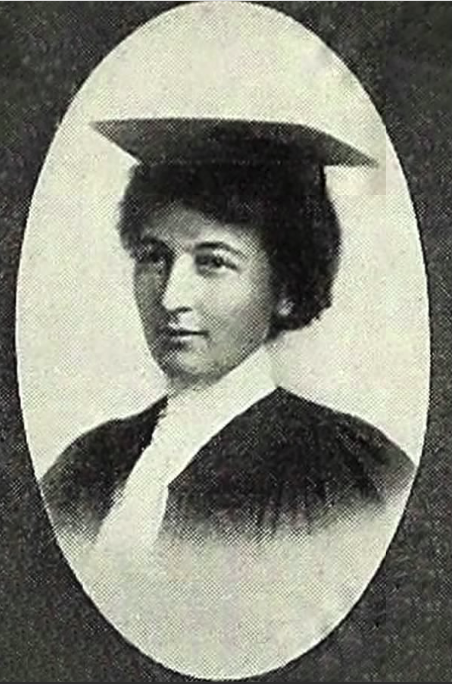 A black and white image of a woman in a graduation cap and gown, from the chest up.