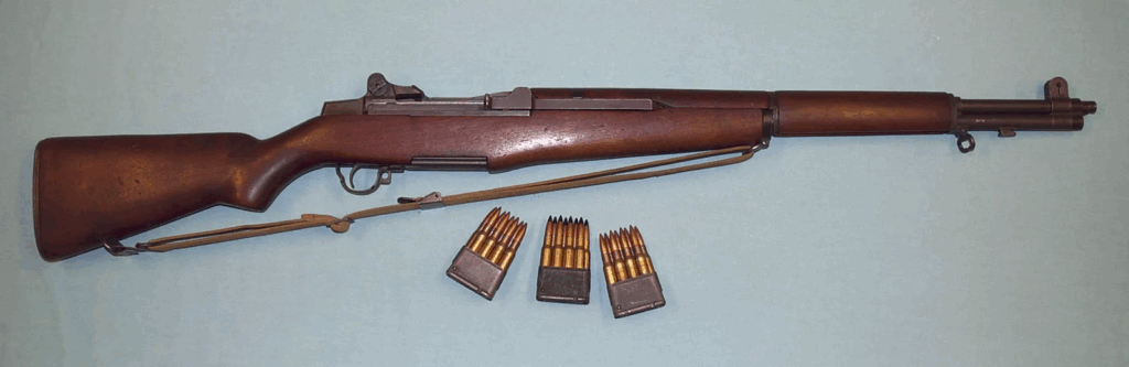 A wooden rifle is lying on a table with three magazines of bullets underneath.