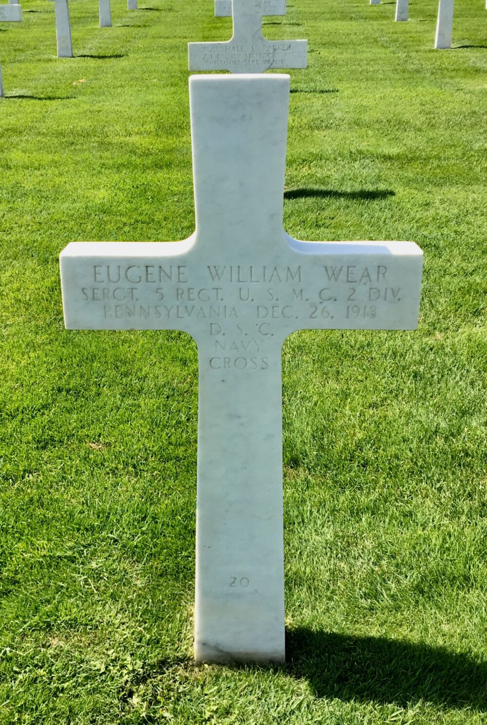 A white, marble cross is engraved with “Eugene William Wear Sergt. 5 Regt. U.S.M.C. 2 Div. Pennsylvania Dec. 26. 1918 D.S.C. Navy Cross”