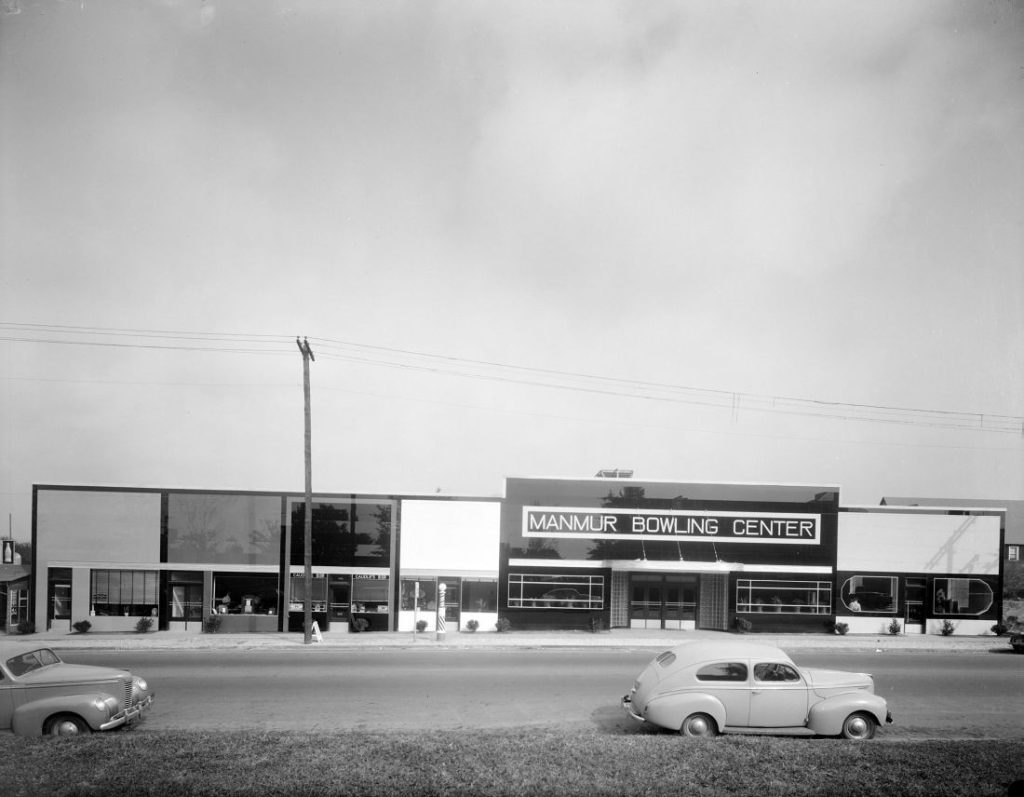 A black and white photograph of a large one-story building labeled 'Man-Mur Bowling Center' There are several cars parked outside.