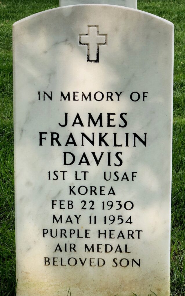A white marble arch headstone is engraved with the words “In memory of James Franklin Davis 1st LT USAF Korea Feb 22 1930 May 11 1954 Purple Heart Air Medal Beloved Son.”