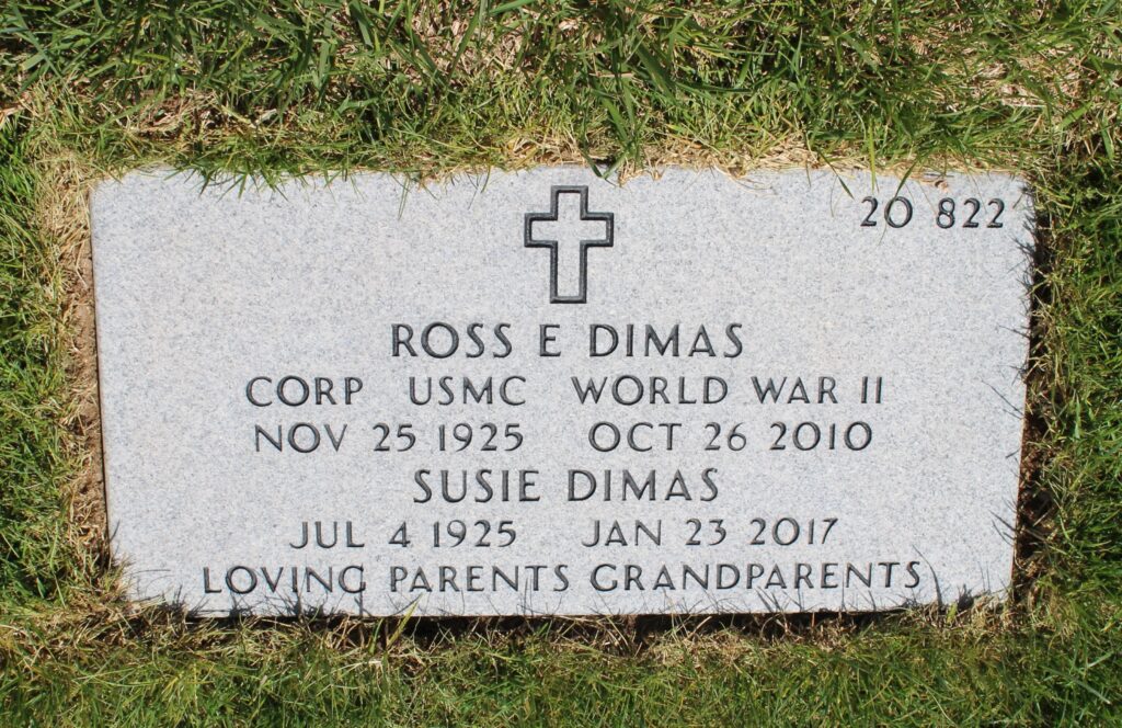 A headstone engraved with a cross followed by “Ross E Dimas Corp USMC World War II Nov 25 1925 Oct 26 2010, Susie Dimas Jul 4 1925 Jan 23 2017, Loving Parents Grandparents.”