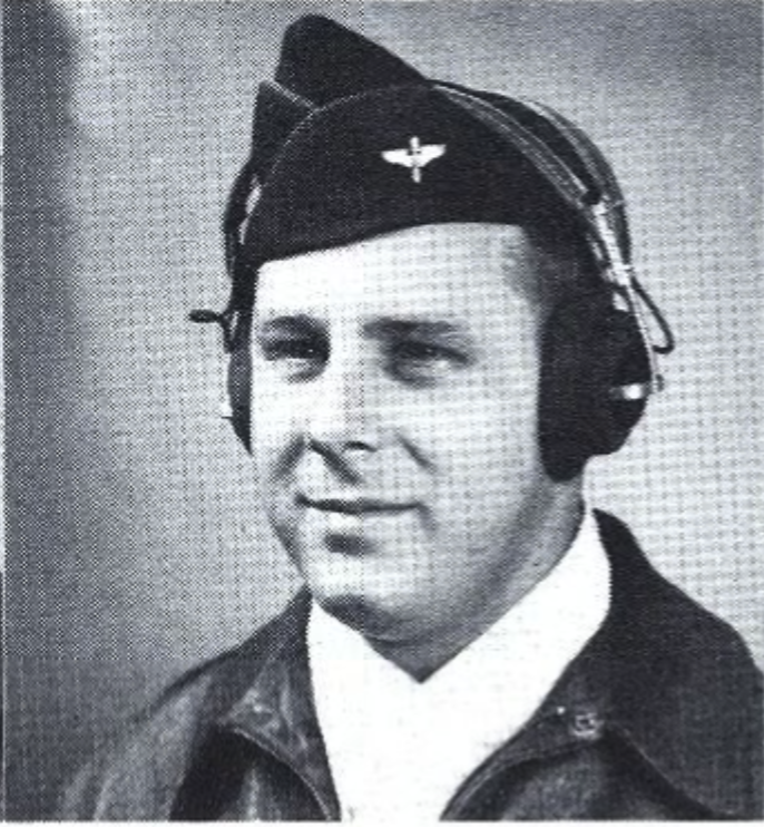 A black and white headshot of a white man in a uniform wearing a cap and headphones.