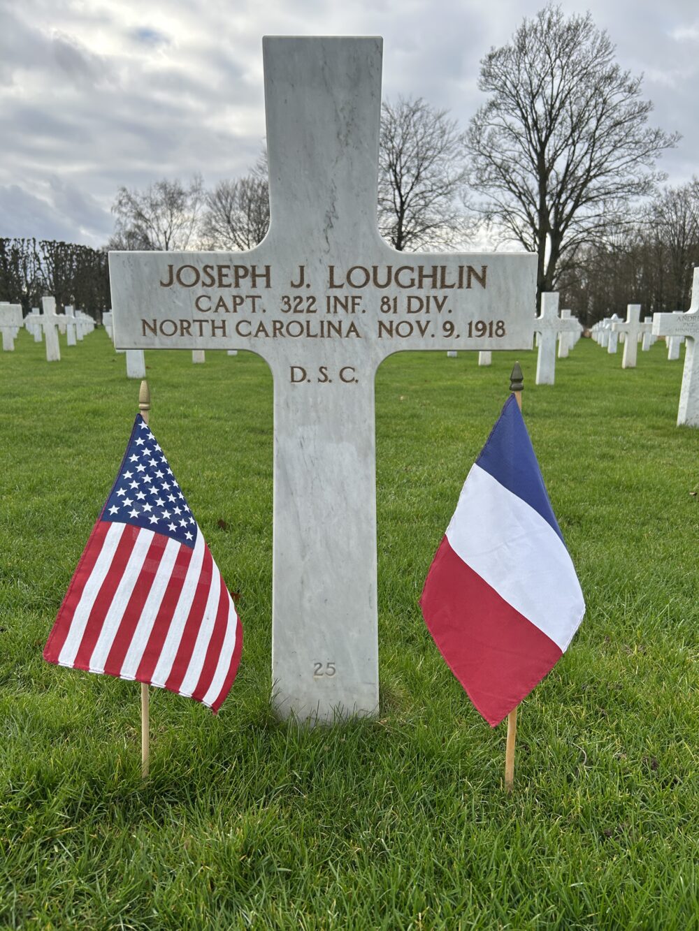 A color picture of a white marble cross engraved with “Joseph J. Loughlin Capt. 322 INF 81 DIV. North Carolina, Nov. 9, 1918. D.S.C.”