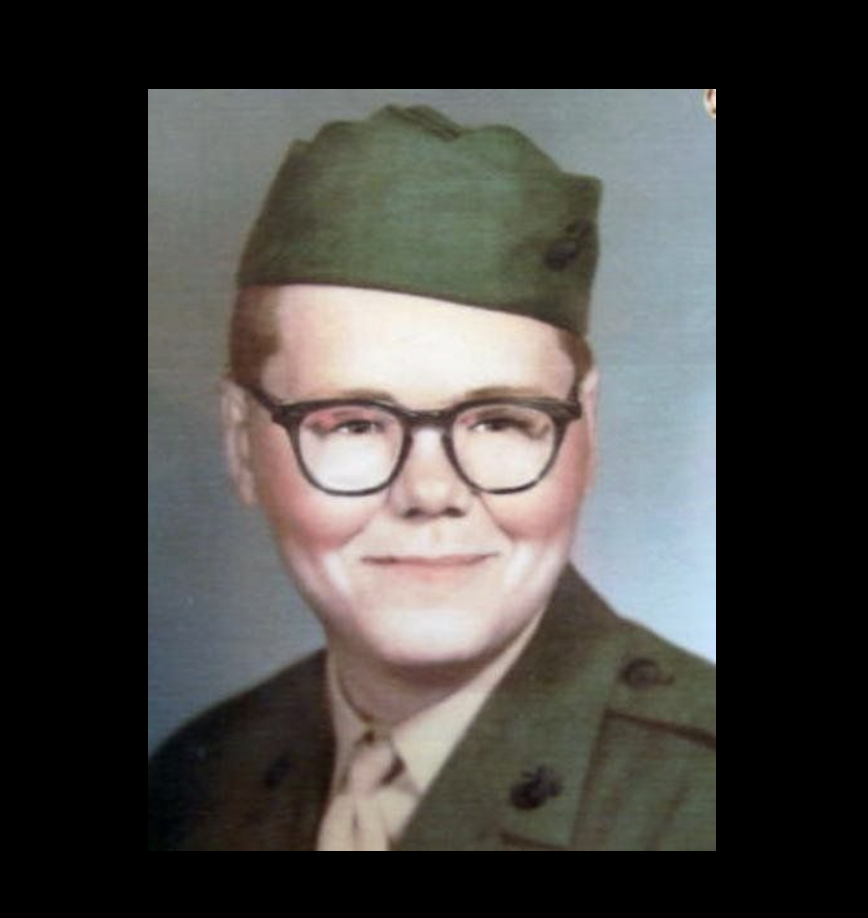 A young man in a Marine Corps uniform and glasses.