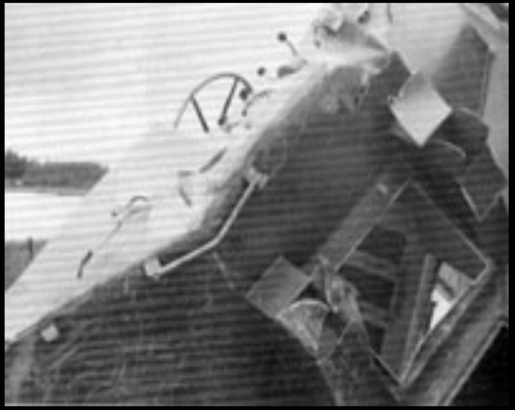 A black and white image of the remains of a boat with damage. 