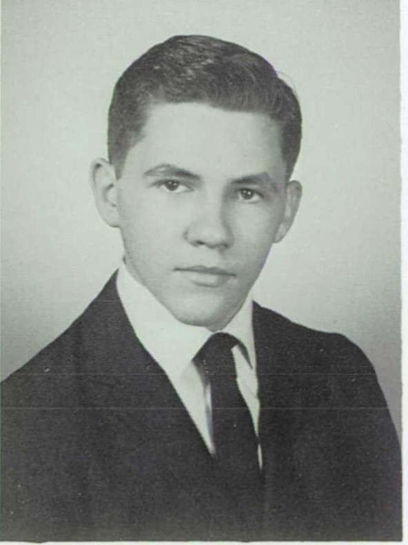A young man with dark hair in a dark suit and tie.