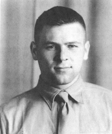 A black and white headshot image of a white man in a uniform shirt and tie.