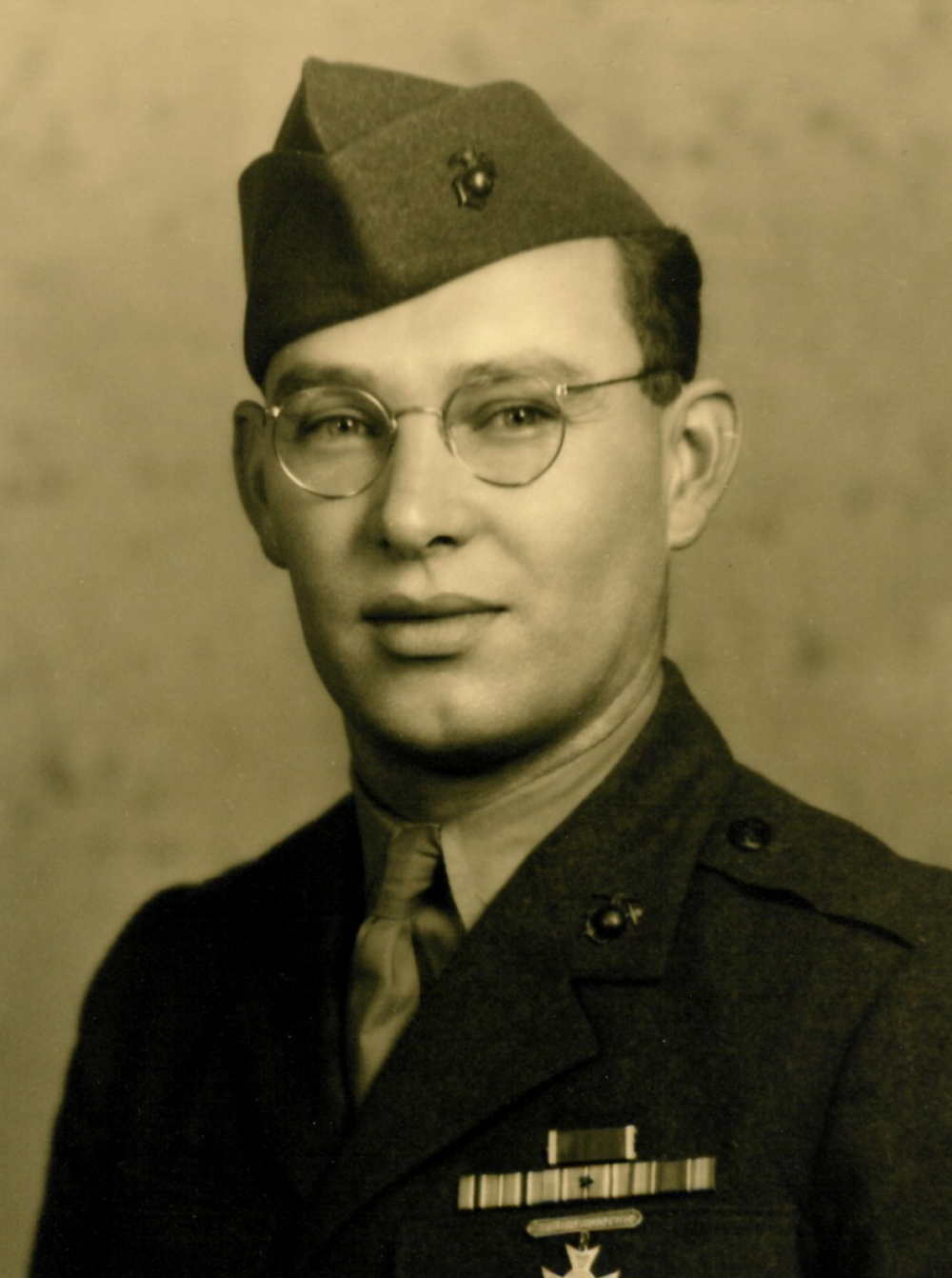 A young man in a Marine Corps uniform and glasses.