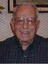 A color headshot of an older White man in glasses. He is wearing a plaid shirt. 