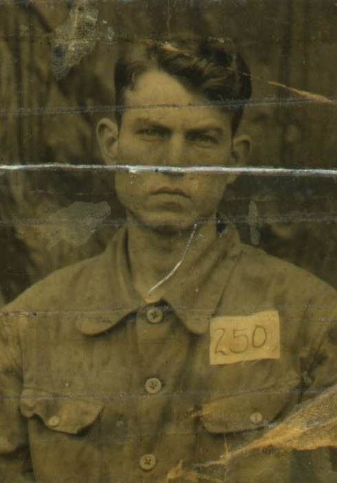 A black and white image of a young White man in a button-down shirt with the number 250 on its chest. 