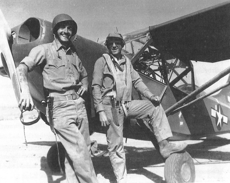 A black and white image of two white men in uniform standing in front of a plane.