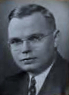 A young man wearing glasses and jacket and tie.