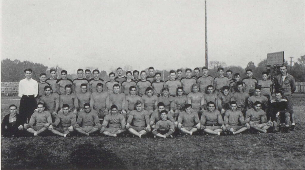 A formal black and white photo of a football team on the field. 