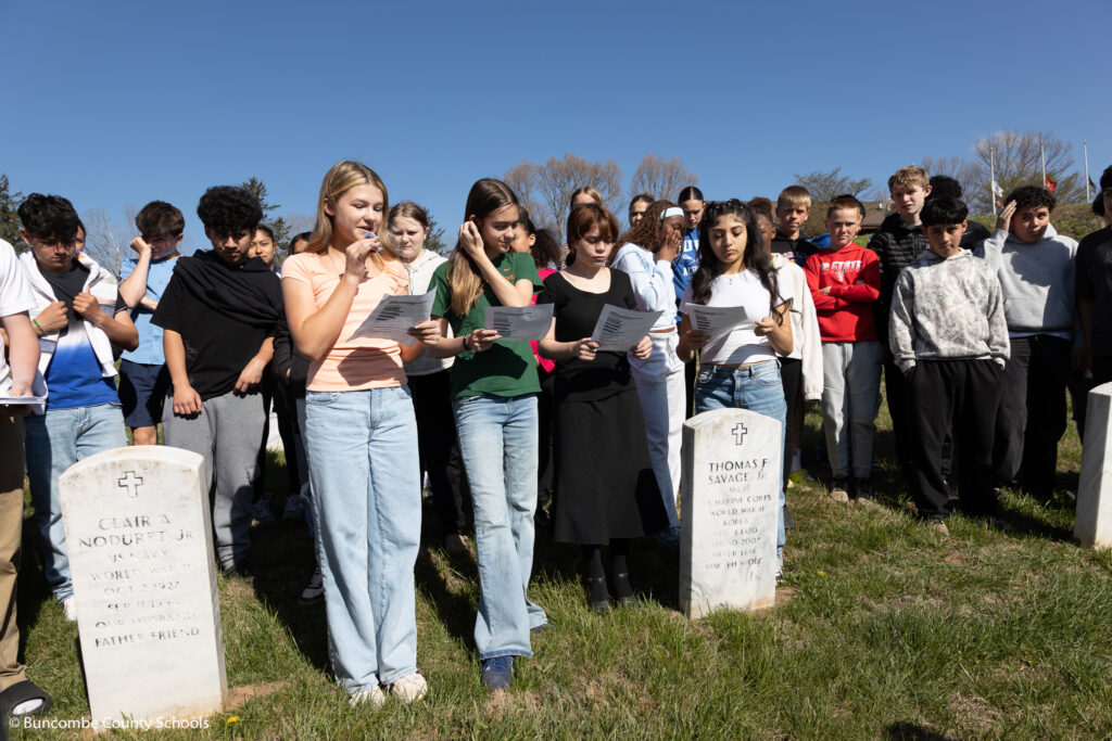 A color image of several students standing in a cemetery.