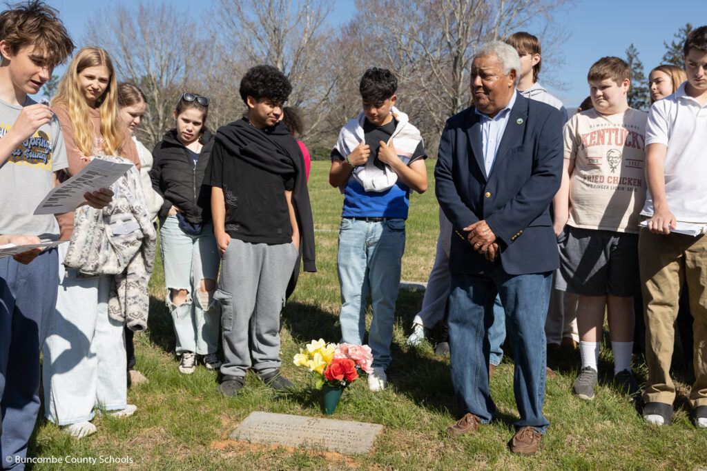 A color photograph of several students standing in a cemetery.