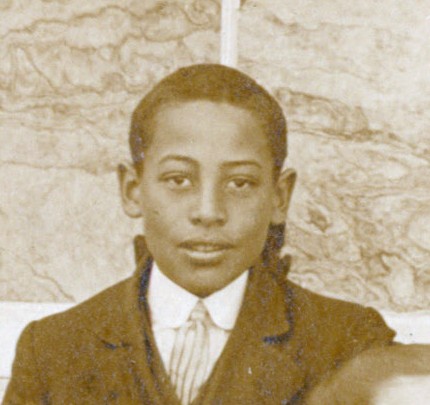A young African American boy in a jacket and tie.
