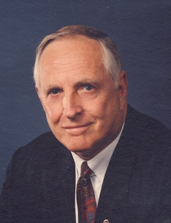 A color headshot of an older White man in a suit and tie.