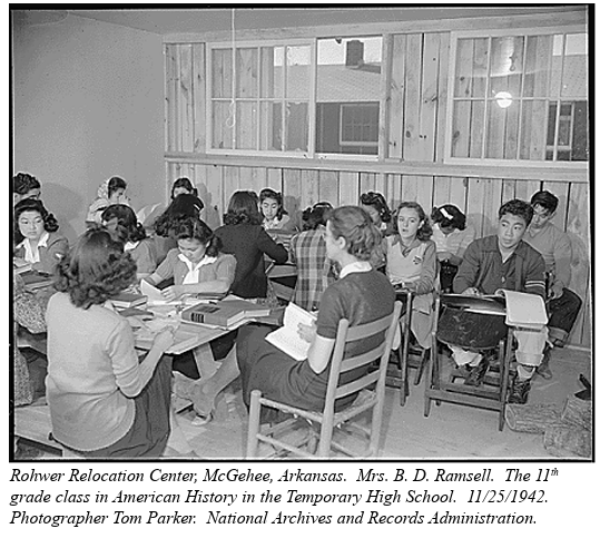 A black and white photo of over a dozen Japanese high school students seated closely together at tables. They have school books out in front of them.