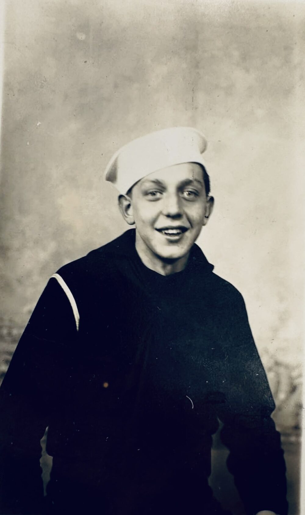 A young White man in a Navy uniform and white hat.