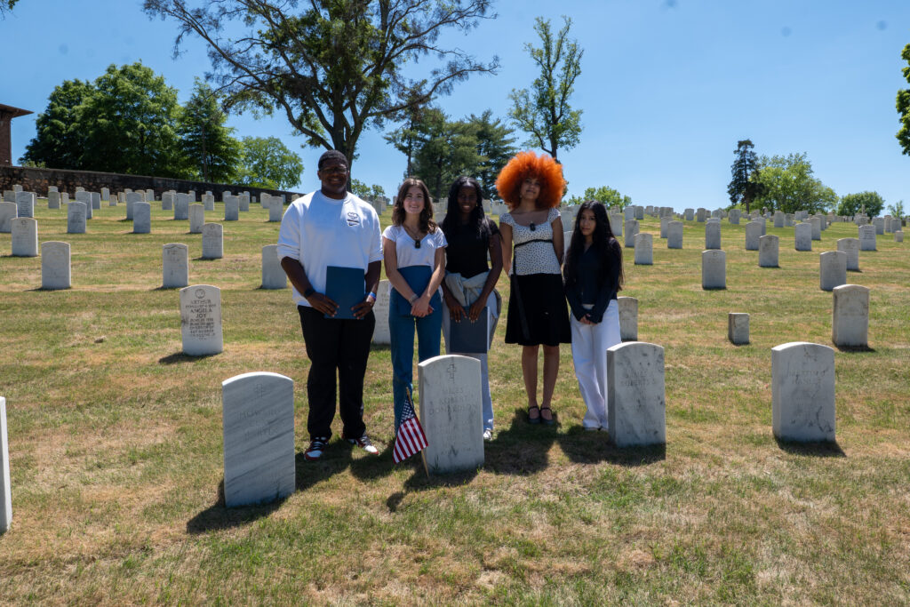 A color image of five students standing in a cemetery.