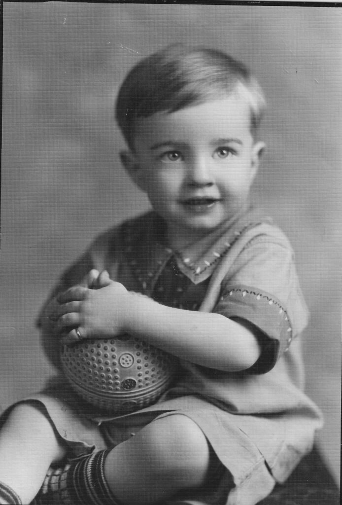 A black and white image of a young boy sitting for a formal portrait.