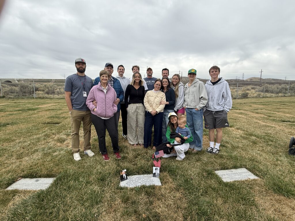 A color image of a group of people standing in a cemetery.
