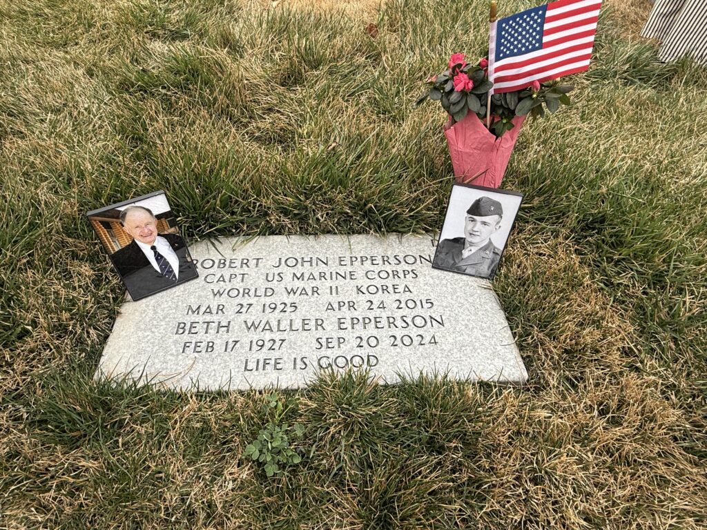 A color image of a grave with photos, flag, and flowers placed.