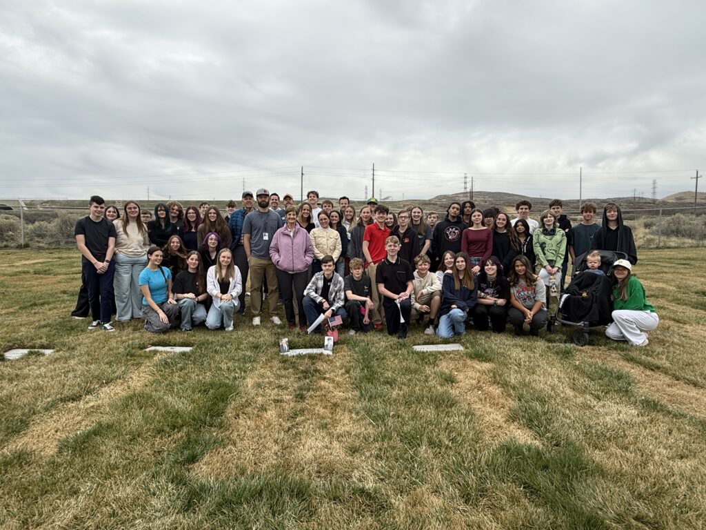 A color image of a large group of people in a cemetery.