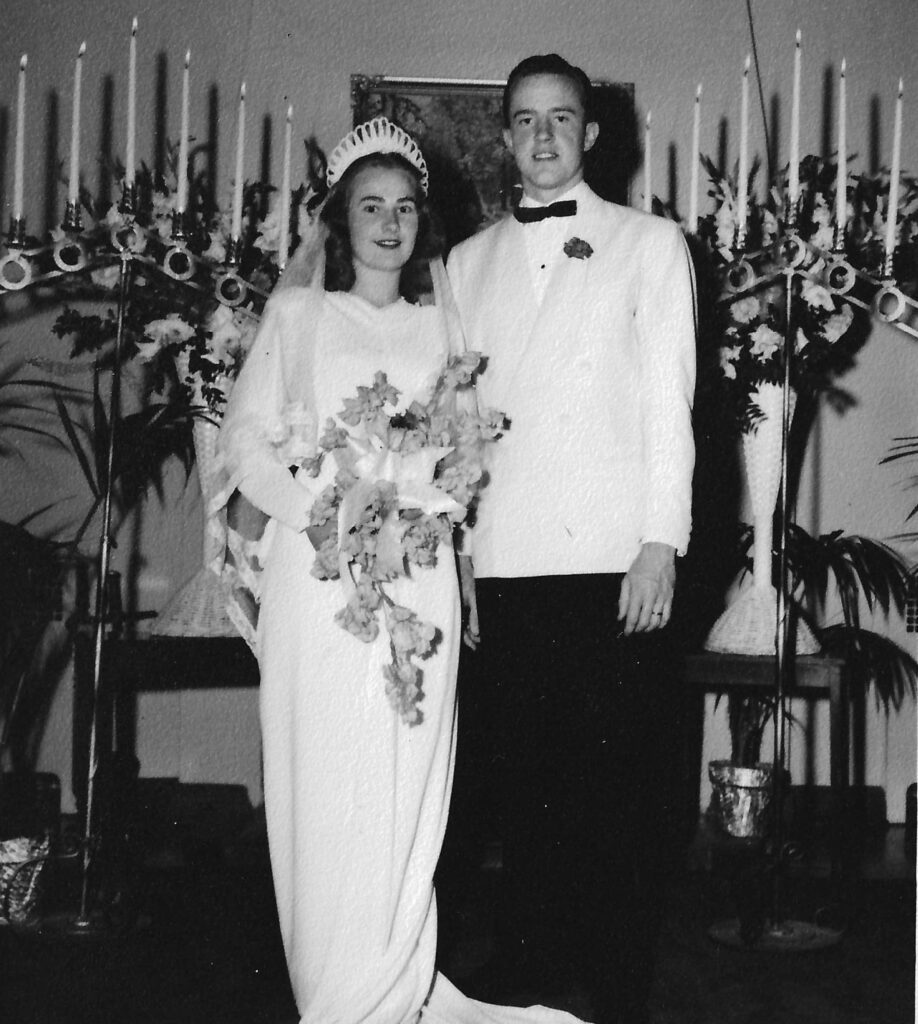 A black and white image of a bride and groom at an altar.