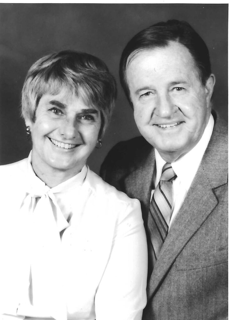 A black and white image of an older White man and woman in formal attire shot from the chest up.