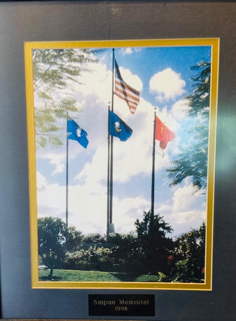A framed color photo of a memorial with multiple flags.