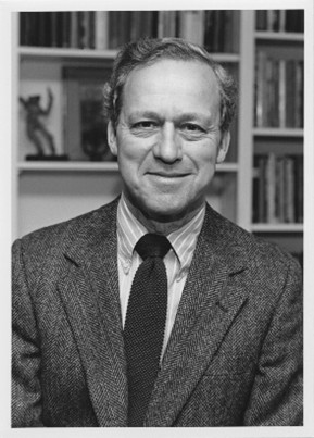 A black and white headshot photo of an older White man in a suit and tie.