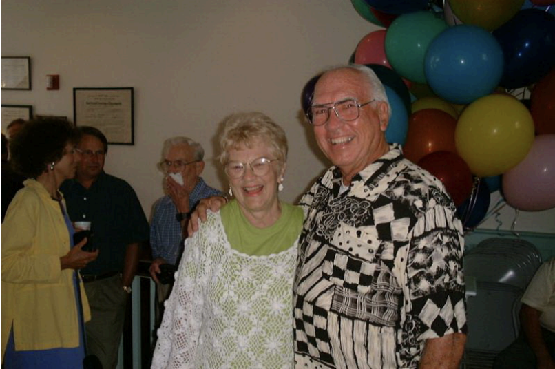 A color photo of an elderly White man and woman at a party.