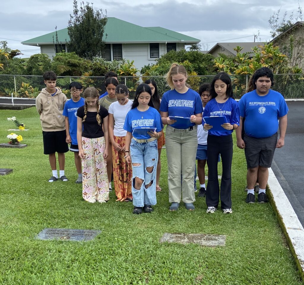 Several students stand in a cemetery. 