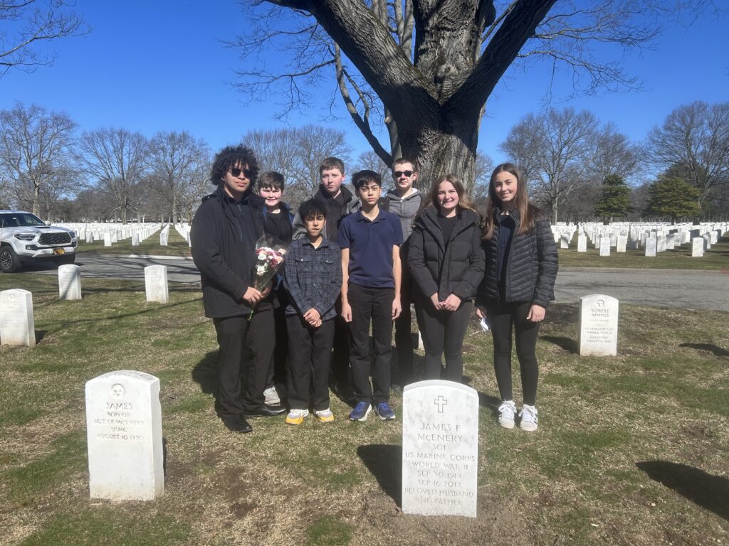 A color image of several students standing in a cemetery