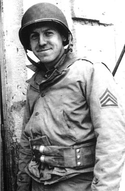 A black and white photo of a young White man standing in uniform from the waist up.